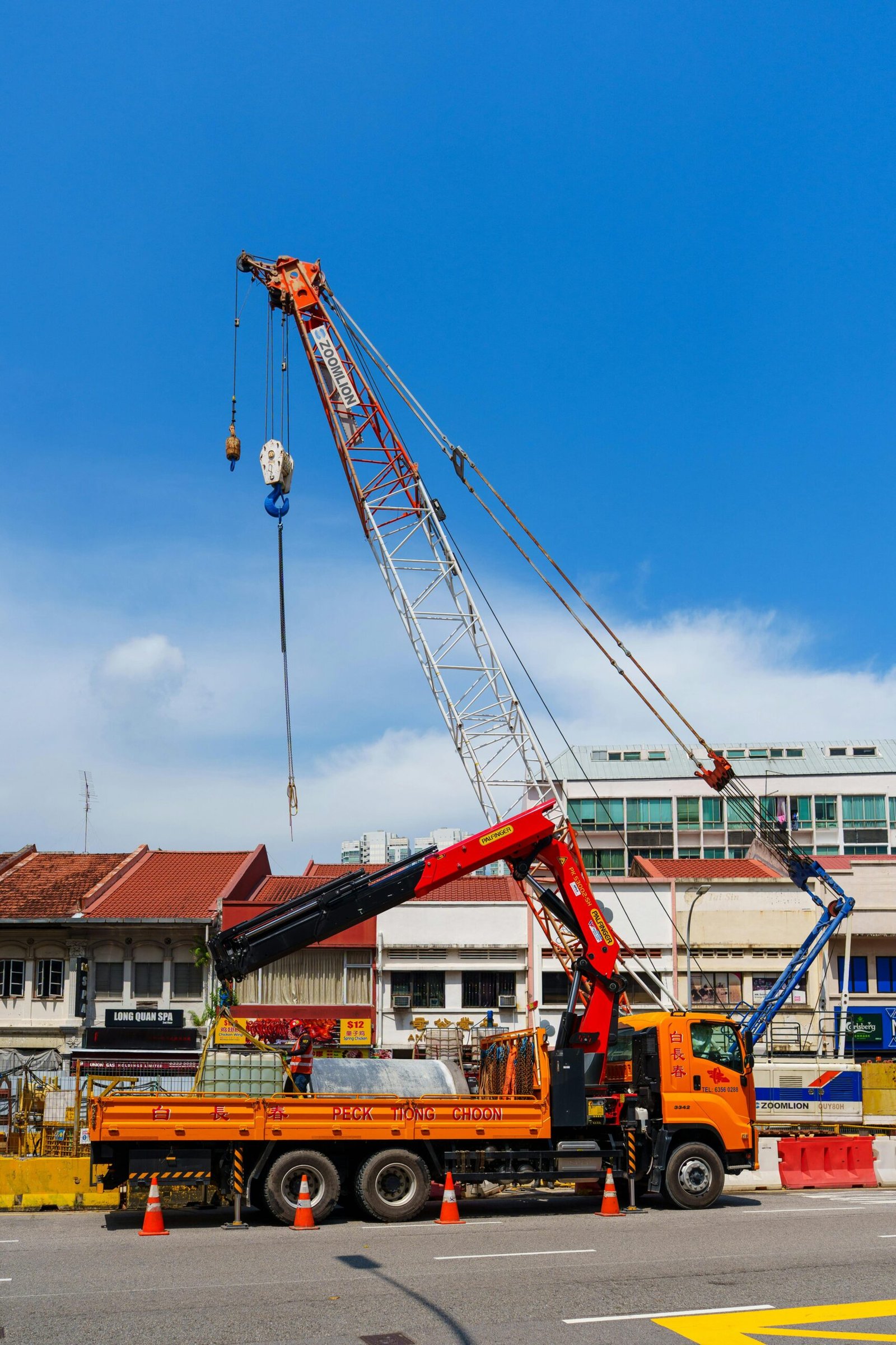A vibrant construction scene with a crane and truck against a clear blue sky in an urban setting.