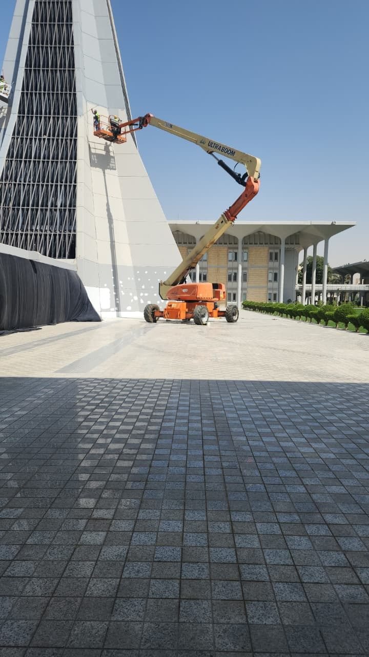 Boom lift raising a worker to a building facade for maintenance