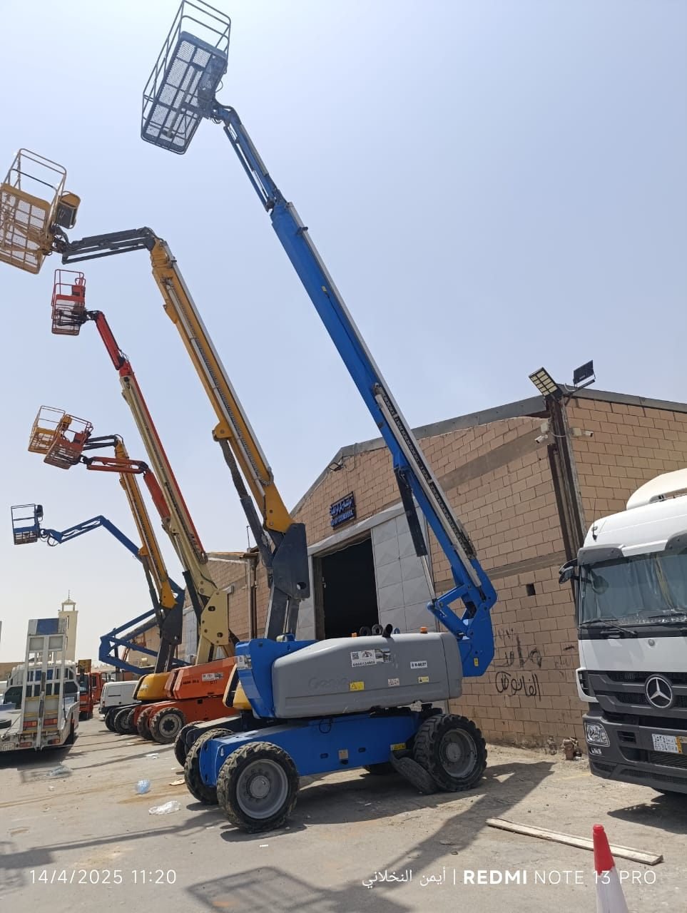 Row of articulating boom lifts extended outside a warehouse
