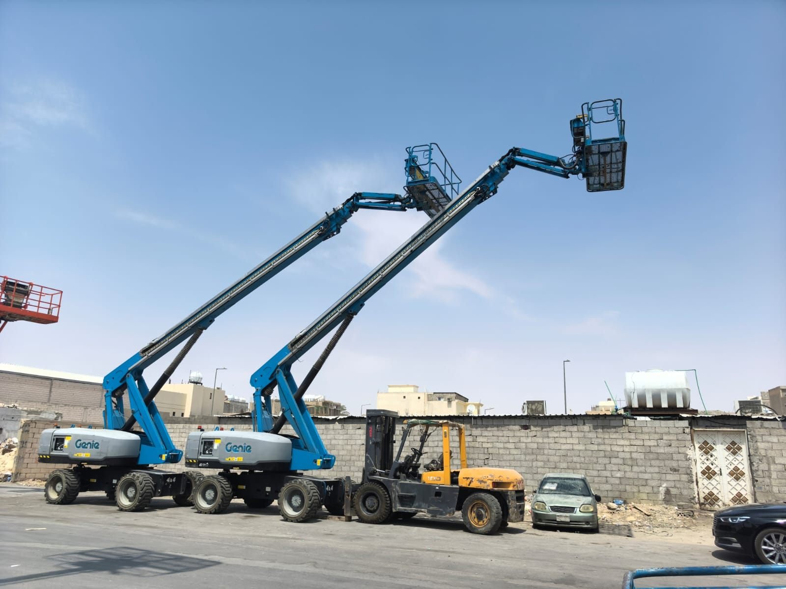 Two boom lifts and a forklift parked on a residential street