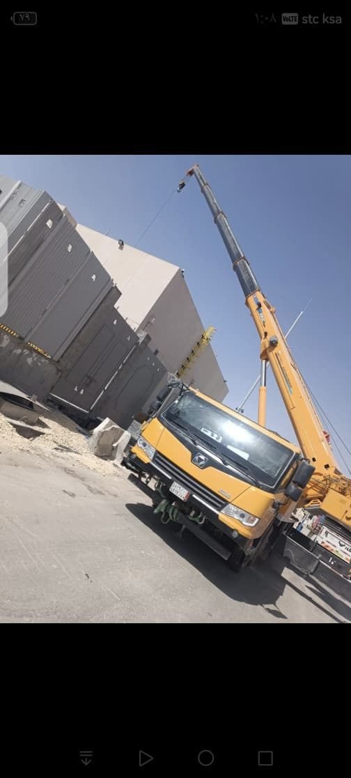 Mobile crane lifting at a construction site with panel containers nearby