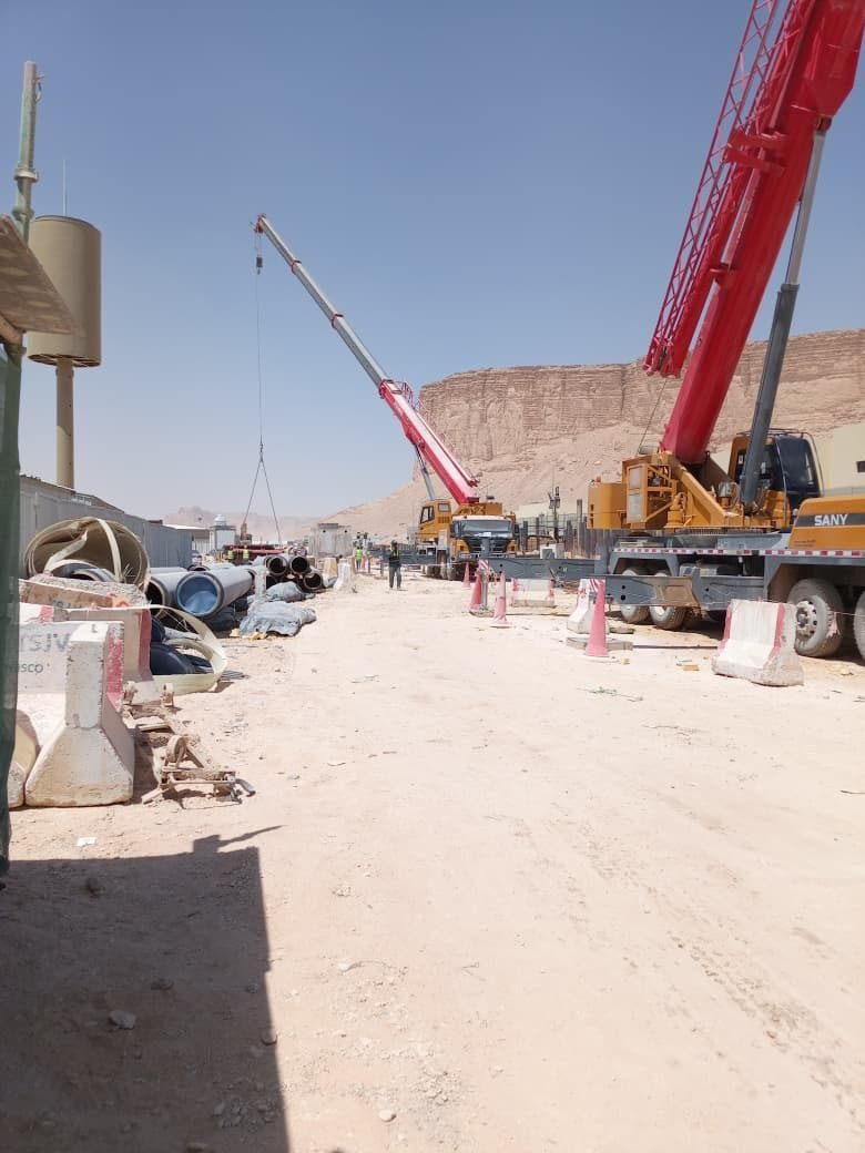 Mobile crane at a pipeline construction site near a rock escarpment