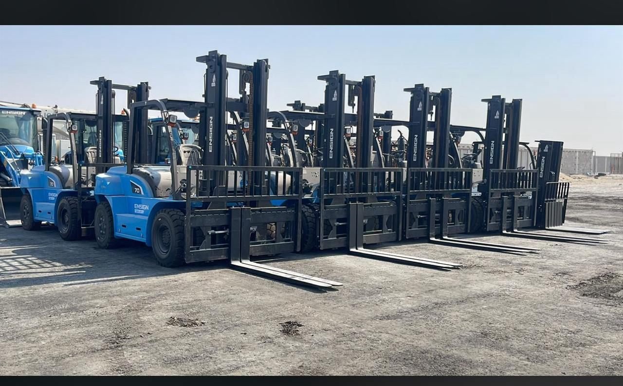 Row of forklifts parked in an outdoor equipment lot
