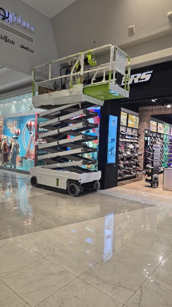 Scissor lift positioned for signage installation inside a shopping mall