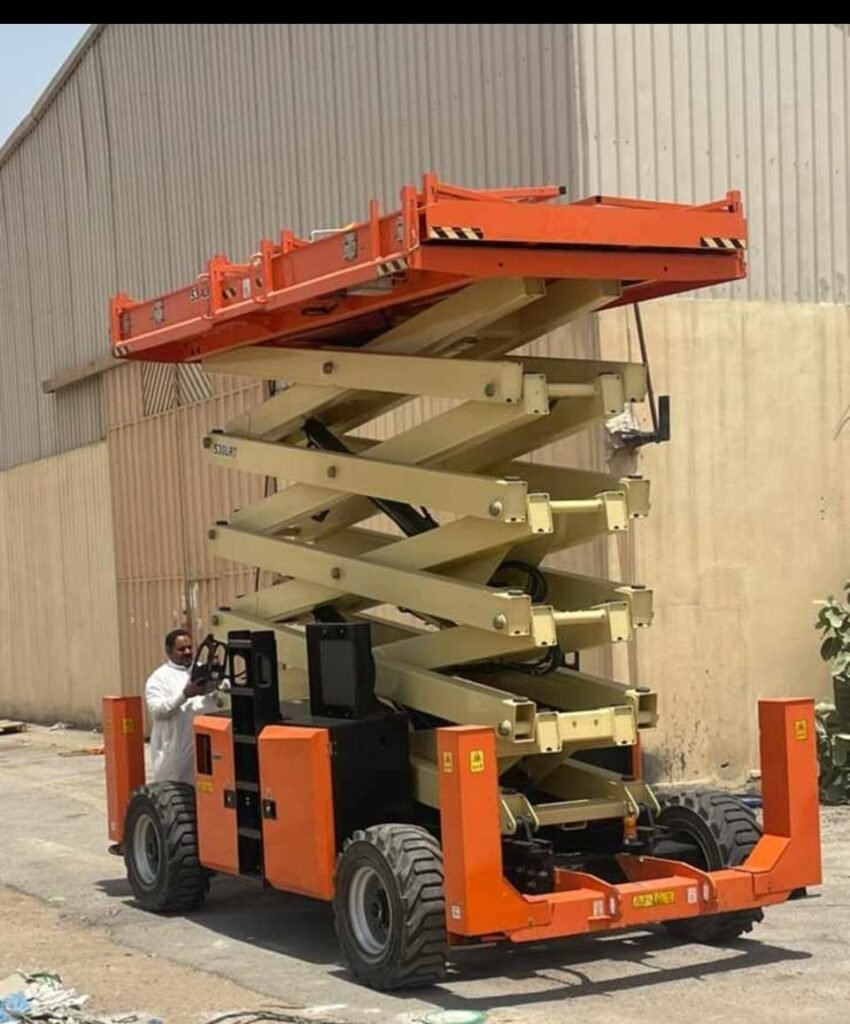 Operator raising a scissor lift platform in an equipment yard