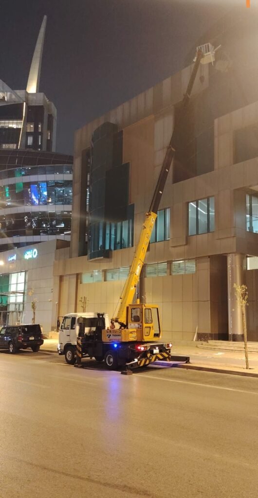 Small truck-mounted crane servicing a commercial building at night